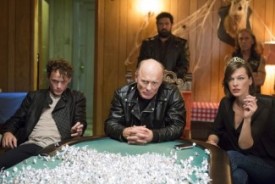 at the table, l-r: Cloten (Anton Yelchin), Cymbeline (Ed Harris), and Queen (Milla Jovovich) meeting with the police to show who's boss