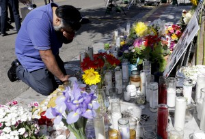 Jose Cardoso pays his respects at a makeshift memorial in front of the IV Deli Mart, where part of Friday night's mass shooting took place by a drive-by shooter Sunday, May 25, 2014, in the Isla Vista area near Goleta, Calif. Sheriff's officials said Elliot Rodger, 22, went on a rampage near the University of California, Santa Barbara, stabbing three people to death at his apartment before shooting and killing three more in a crime spree through a nearby neighborhood. (AP Photo/Chris Carlson)